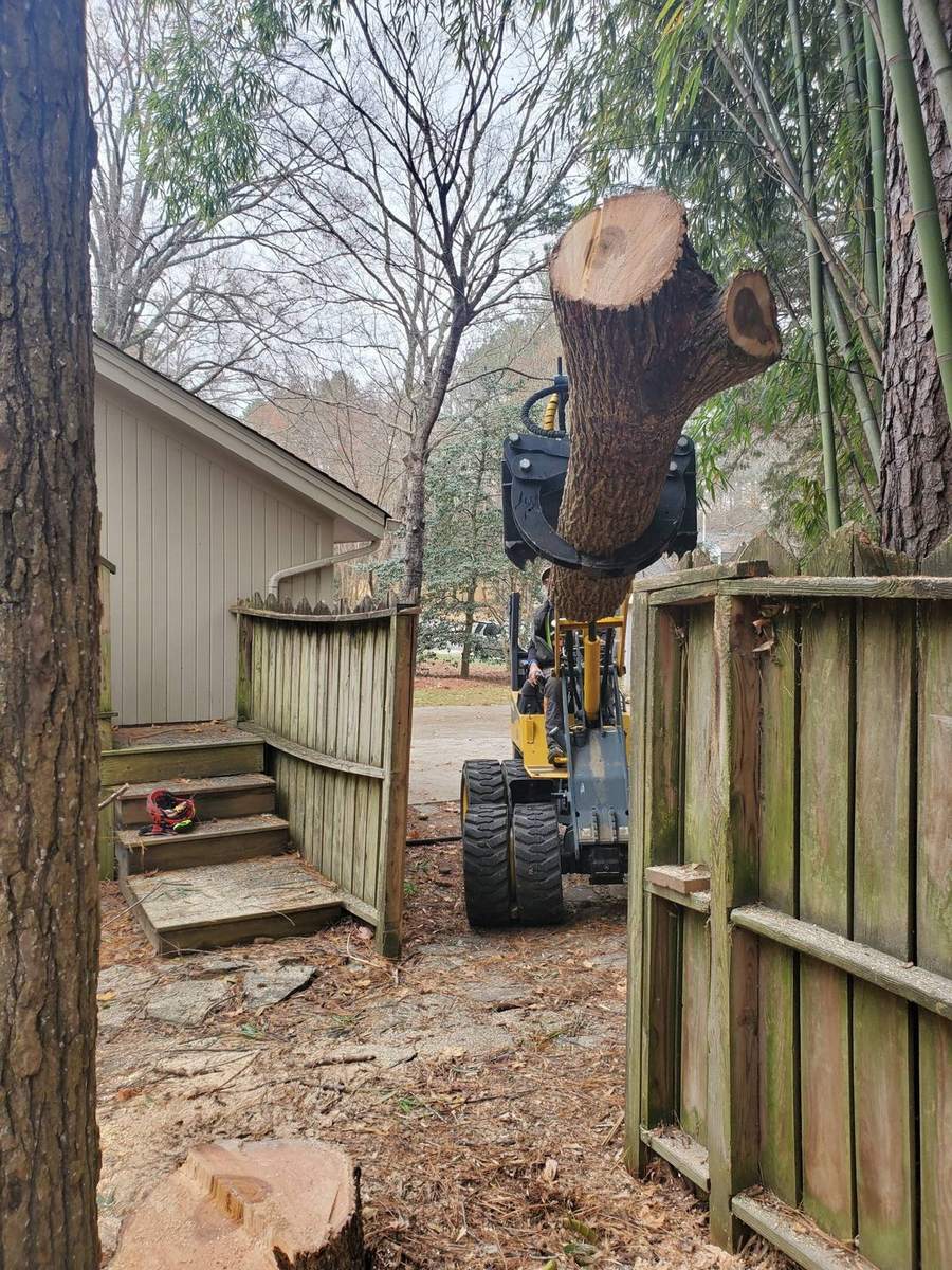 A compact loader coming through a narrow backyard gate